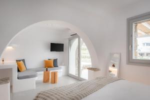 a white bedroom with a bed and a window at Koumi Homes Mykonos in Elia