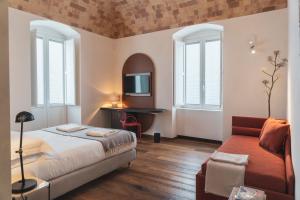 a bedroom with a bed and a couch and windows at Palazzo Fontana B&B e SPA in Gravina in Puglia