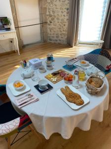 - une table blanche avec des aliments pour le petit-déjeuner dans l'établissement Le Cocon de Curson chambre d'hôtes, à Chanos-Curson