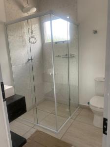 a glass shower in a bathroom with a toilet at VILLAGE Host Hotel in Pedra Bela