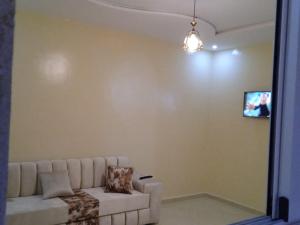 uma sala de estar com um sofá e uma televisão na parede em Appartement à louer Tiznit 2 em Tiznit