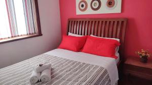 a bedroom with red pillows and a bed with two towels at Pousada Jupter in Teresópolis