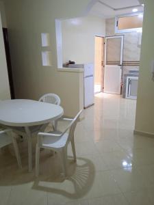 uma mesa branca e cadeiras num quarto com uma cozinha em Appartement à louer Tiznit 2 em Tiznit
