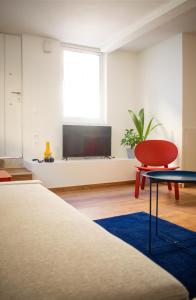 a room with a tv and a red chair and a table at RYB Colour Apartment in Patra