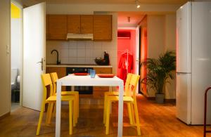 a kitchen with a white table and yellow chairs at RYB Colour Apartment in Patra