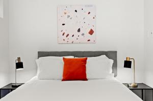 um quarto com uma cama branca e uma almofada vermelha em Kasa The Addison San Francisco em São Francisco