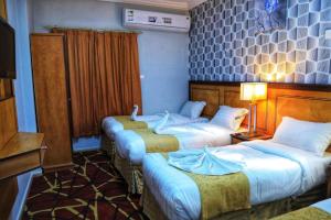 une chambre d'hôtel avec trois lits et une télévision dans l'établissement Manart Al Misk Hotel, à La Mecque
