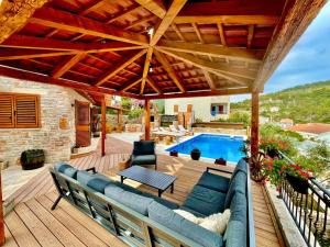 un patio con sofá, mesa y piscina en Šolta Stone House en Stomorska