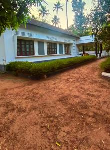 a white building with a dirt yard in front of it at Zebra Hostels in Varkala