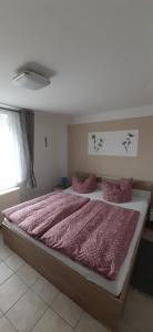 ein Schlafzimmer mit einem großen Bett mit rosa Daunendecke in der Unterkunft Familie Fritz in Gager