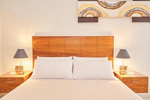 1 dormitorio con 1 cama con cabecero de madera y 2 lámparas en El Hostal de Violeta en Tomelloso