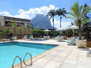 una piscina con sillas y palmeras y un edificio en Apart Hotel Barra Leme com Vista Mar Maravillhosa B1-002o, en Río de Janeiro