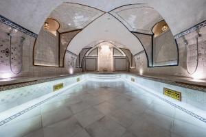 an indoor swimming pool with a tile floor and a ceiling at Atrium Konak in Novi Sad