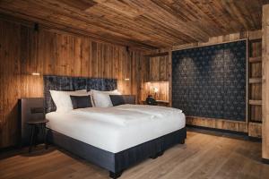1 dormitorio con 1 cama grande y paredes de madera en Luxury Spa Chalet Lum d'Or, en Selva di Val Gardena