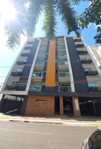 un grand bâtiment avec un palmier devant lui dans l'établissement Novo central 2 quartos wifi/garagem/elevador, à Foz do Iguaçu