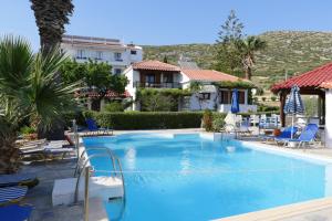 a pool at a hotel with chairs and a building at Jasmine apartments in Pythagoreio