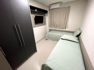 a small room with two beds and a cabinet at Residencial Dinapoli in Foz do Iguaçu