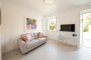 a white living room with a couch and a tv at Via Zug in Castiglioncello
