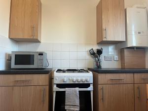 uma cozinha com um fogão e um micro-ondas em Addington House 4 beds em Londres