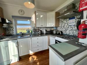 cocina con armarios blancos y fogones en BAYVIEW self-catering coastal bungalow in rural West Wight, en Freshwater