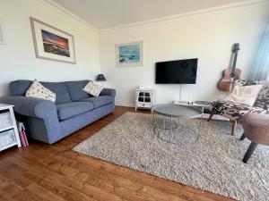 a living room with a blue couch and a tv at BAYVIEW self-catering coastal bungalow in rural West Wight in Freshwater