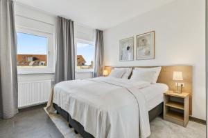 a bedroom with a large white bed and two windows at Empire Living: Denzlingen Marktplatz in Denzlingen