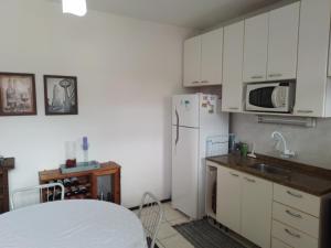 eine Küche mit weißen Schränken und einem weißen Kühlschrank in der Unterkunft Apt com vista para o mar in Capão da Canoa