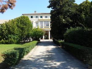 un grande edificio bianco con un sentiero davanti di Villa Carrer a Porto Viro