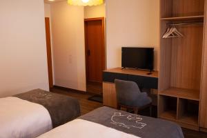 ein Hotelzimmer mit 2 Betten, einem Schreibtisch und einem TV in der Unterkunft Hôtel de L'Ours in Courroux