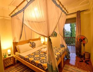 a bedroom with a canopy bed and a balcony at Cycad Entebbe Guest House in Entebbe