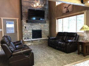 a living room with two leather couches and a fireplace at Heated Floors, Hot Tub, Grill in Island Park