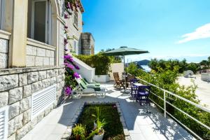 balcón con sillas, mesas y sombrilla en Apartments Dubrovnik Seven, en Dubrovnik
