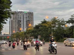un gruppo di persone che cavalcano motociclette lungo una strada di città di Căn hộ cao cấp tầng cao đối diện Aeon Mall 2PN/2PT a Hanoi