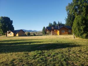 a large field with two houses in the background at Altos Del Molino in Trevelín