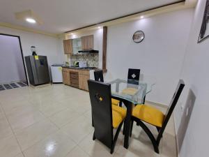 Las Margaritas apartments, Pereira City Centre في بيريرا: مطبخ مع طاولة زجاجية وكراسي صفراء