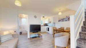 a living room with a flat screen tv and a kitchen at 39 Strawberry Hill, Tolroy Manor in Hayle