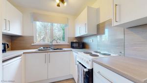 a kitchen with white cabinets and a sink and a window at 39 Strawberry Hill, Tolroy Manor in Hayle