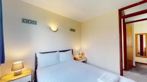 a bedroom with a white bed and two night stands at 39 Strawberry Hill, Tolroy Manor in Hayle +2 photos