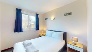 a bedroom with a bed with blue curtains and a window at 39 Strawberry Hill, Tolroy Manor in Hayle