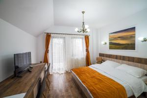 1 dormitorio con 1 cama y TV de pantalla plana en Drag de Bucovina en Gura Humorului