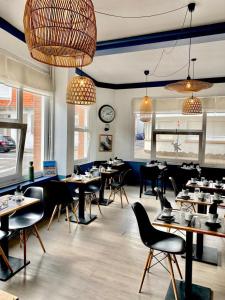 a dining room with tables and chairs and a clock at Hôtel Jules in Le Touquet-Paris-Plage