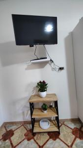 una televisione su un muro con un tavolino con una pianta di Almiva alloggio confortevole vicino alla Scala dei Turchi a Realmonte