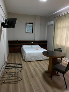 1 dormitorio con cama, mesa y escritorio en Map Hotel en Lages