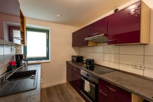 a kitchen with purple cabinets and a sink at Börde-Apartment 5 in Vahldorf