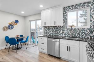 una cocina con armarios blancos y una mesa con sillas azules en Luxurious Fully Renovated House w/ New Hot Tub! en Sandy