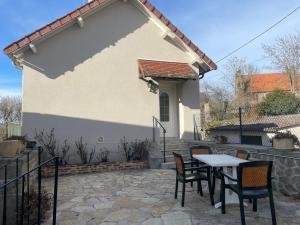 une terrasse avec une table et des chaises devant une maison dans l'établissement Gîte des Buis, à Moutier-Rozeille