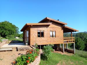 une petite maison en bois dans une cour fleurie dans l'établissement Cabana aconchegante, à Novo Hamburgo