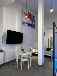 uma sala de estar com uma mesa e uma televisão na parede em Loft familiar "PISCINA SEVILLA CENTRO" em Sevilha