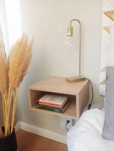 a nightstand with books and a lamp next to a bed at Charming Studio in Stellenbosch - The Valley Stay in Stellenbosch