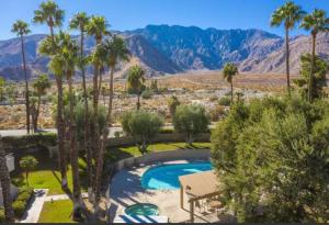 a swimming pool with palm trees and mountains in the background at Palm Springs Perfect Getaway in Palm Springs